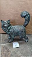 Side view of cat statue showing full body and raised bushy tail with curled top.