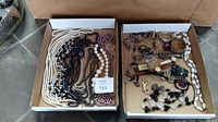 Box filled with assorted necklaces, watches, brooches, rings, and earrings.