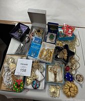 Assorted vintage-style pins, brooches, necklaces, and monogram stickers arranged on table.