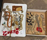 Overview of assorted costume jewelry including necklaces and other pieces spread on two trays.