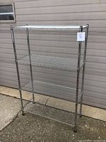 Front view of the four-tier metal wire shelving unit showing chrome finish and adjustable shelves.