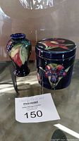 Small Moorcroft pottery vase and trinket box on glass surface under lighting