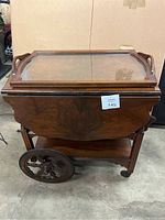 Full view of the closed tea trolley with glass tray on top, showcasing decorative wheel design and wooden finish.