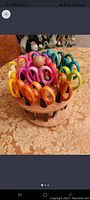 Circular swiveling wood caddy holding colorful decorative scissors with patterned blades