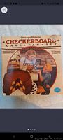 Box image of Chicago Metallic Checkerboard Cake Pan Set with image of children and a checkerboard cake on it