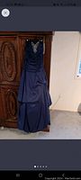 Full view of the midnight blue formal dress showing ruched bodice, embellished neckline, and layered skirt.