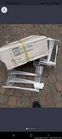 14 white metal flower box and basket holders packed and arranged on ground with box