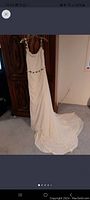 Full length of the ivory wedding dress hanging, showing the flowing skirt and train.