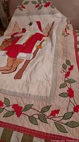 Christmas quilt showing Santa Claus design with red coat, brown boots, and holly berry leaf border