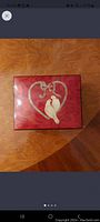 Closed view of rectangular wood inlaid jewelry box with a heart and two white birds on top.