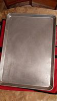 Top view of a large rectangular metal baking tray showing its smooth surface and slightly rounded edges.