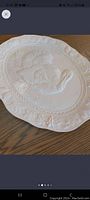 White ceramic turkey-shaped serving platter with embossed design and decorative edge detail on wood table