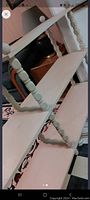 Photo showing two-tier shelf with turned wooden supports finished in light cream paint