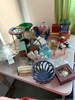 Overview of table showing multiple decorative items including Arthur Court cake plate, candle holders, vases, bookmarks, and boxed cookbooks.