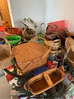 Overview photo showing a collection of assorted wicker baskets of varied styles and sizes on a glass table, including the picnic basket and duck-shaped basket.