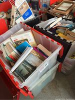 Four plastic bins filled with assorted books, showing titles including various cooking and non-fiction books.