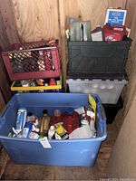Overview of storage bins and crates holding various automotive and cleaning fluids inside a wooden shed.
