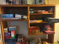 Overall view of shelf containing assorted boxed board and party games including Catch Phrase, Taboo, Pictionary, Memory, Boggle, and more.