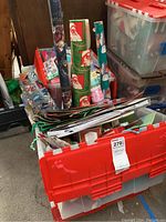 First photo showing red plastic bin filled with rolled Christmas wrapping paper and other giftwrap materials