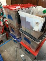 Stack of six large plastic bins with red and gray lids labeled for Christmas storage.