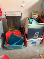 Photo showing black plastic file holder on top of plastic storage bins containing various journals, binders, and papers in different colors and sizes.