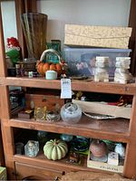 Shelf with various decorative items including marble bookends, ceramic pumpkins, vases, and storage boxes