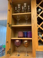 Glass cabinet showing various Mikasa glasses arranged on three shelves.