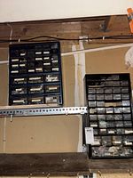 Two plastic storage containers mounted on garage wall, showing overall lot including multiple drawers with hardware inside.