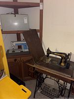 Photo showing vintage Singer Touch & Sew floor model sewing machine in wooden cabinet with treadle base.