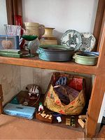 Photo showing stoneware bowls, decorative plates with Native American and wolf designs, glass vases and bowls on wooden shelves.