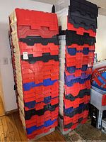 Two stacks of plastic storage totes with red, black, and blue lids and clear bodies