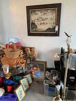 Wide view showing the framed mountain landscape painting above a glass table, along with other assorted framed artworks and items around it.