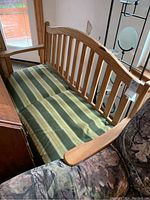 Full view of the wooden bench with green and yellow striped cushions.