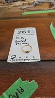 Image showing the 10K gold ring on a white paper tag labeled 10K gold ring with lot number 261.