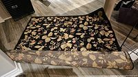 Full view of the polyester floral area rug partially rolled, showing floral pattern and backing.