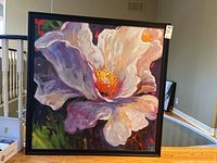 Front view of framed canvas painting depicting large white and purple flower in black wood frame
