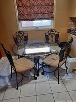 Front view of the round glass-top table and four chairs under a kitchen window