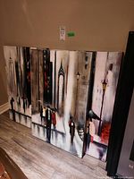 Three canvas prints leaning against a wall, showing urban scenes with people and buildings