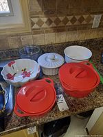 Overview photo of all dishes on kitchen countertop showing three Corningware lidded dishes, one unlidded Corningware dish, and one Full Bloom Skye McGhie bowl with floral pattern.