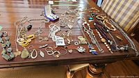 Overview of various costume jewelry pieces including necklaces, earrings, rings, and pendants spread on a table.