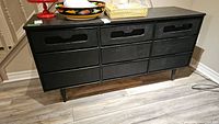 Front view of the black painted 9 drawer dresser showing all drawers and angled legs.