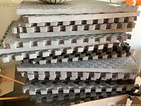 Stack of 22 puzzle foam floor mats showing thickness and interlocking puzzle edges in grey and beige shades.