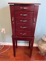 Front view of the jewellery cabinet showing five drawers with silver handles and two side doors.