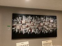 Front view of the large abstract print on canvas hung on wall above white chairs.