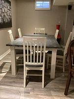 Front view of rectangular harvest table with six straight-back chairs.