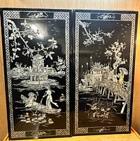 Two black lacquer panels side by side showing the full front design of both with scenes, borders and details visible.