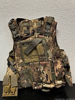 Front view of the camouflage hunting vest showing multiple pouches and attachment points