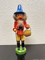 Front view of nutcracker showing detailed clothing, beard, basket and cane.