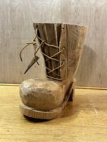 Front angled view of the carved wooden boot showing leather laces and carved details.