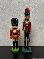 Set of two painted wooden nutcrackers standing on a flat surface against a white wall.
